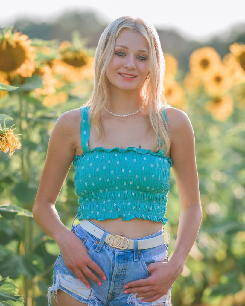 senior girl in a blue top in a sunflower field