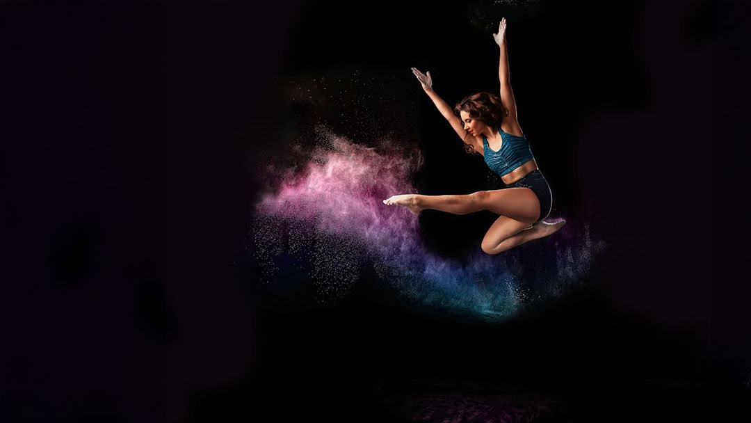 A dancer jump pose in a black background and creative colorful flour.