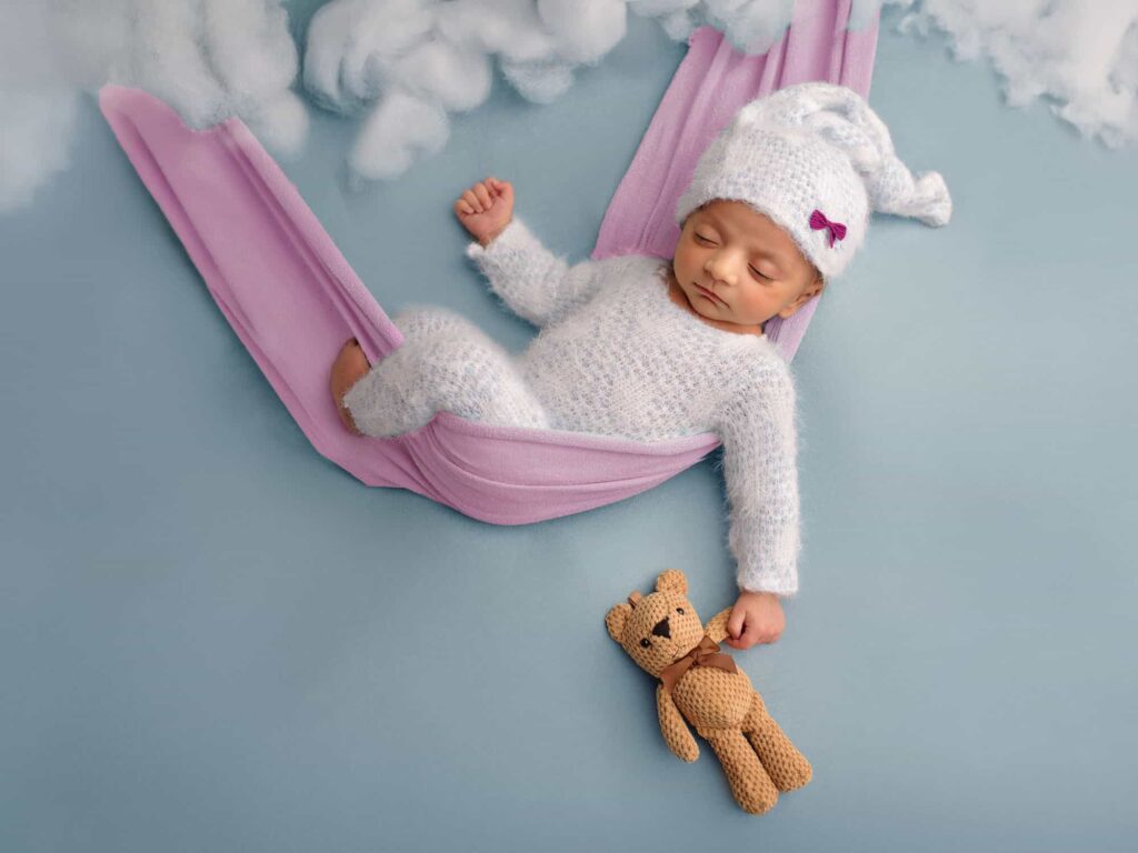 newborn-photo-in-a-swing-with-clouds-and-teddy-bear